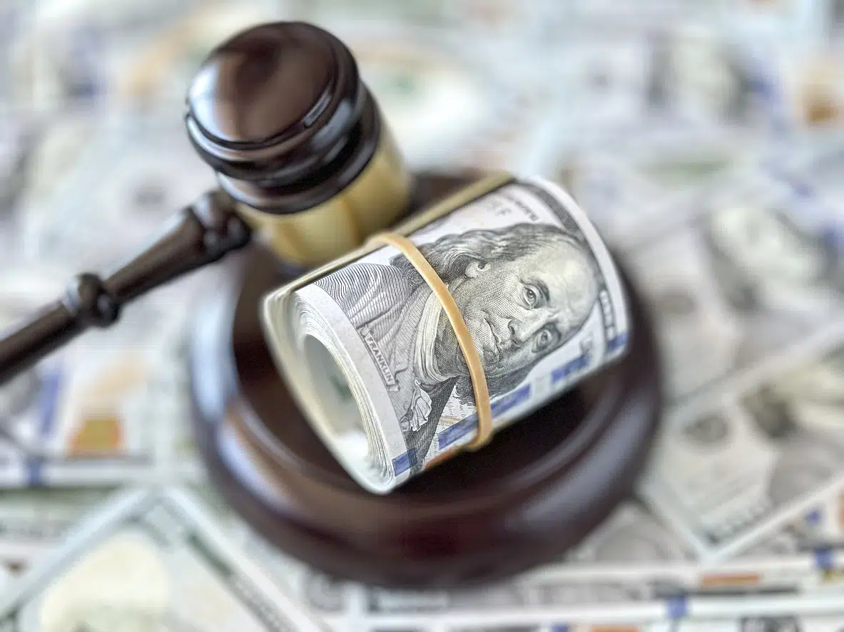 A judge's gavel rests on a surface covered with bundles of rolled US dollar bills for bail