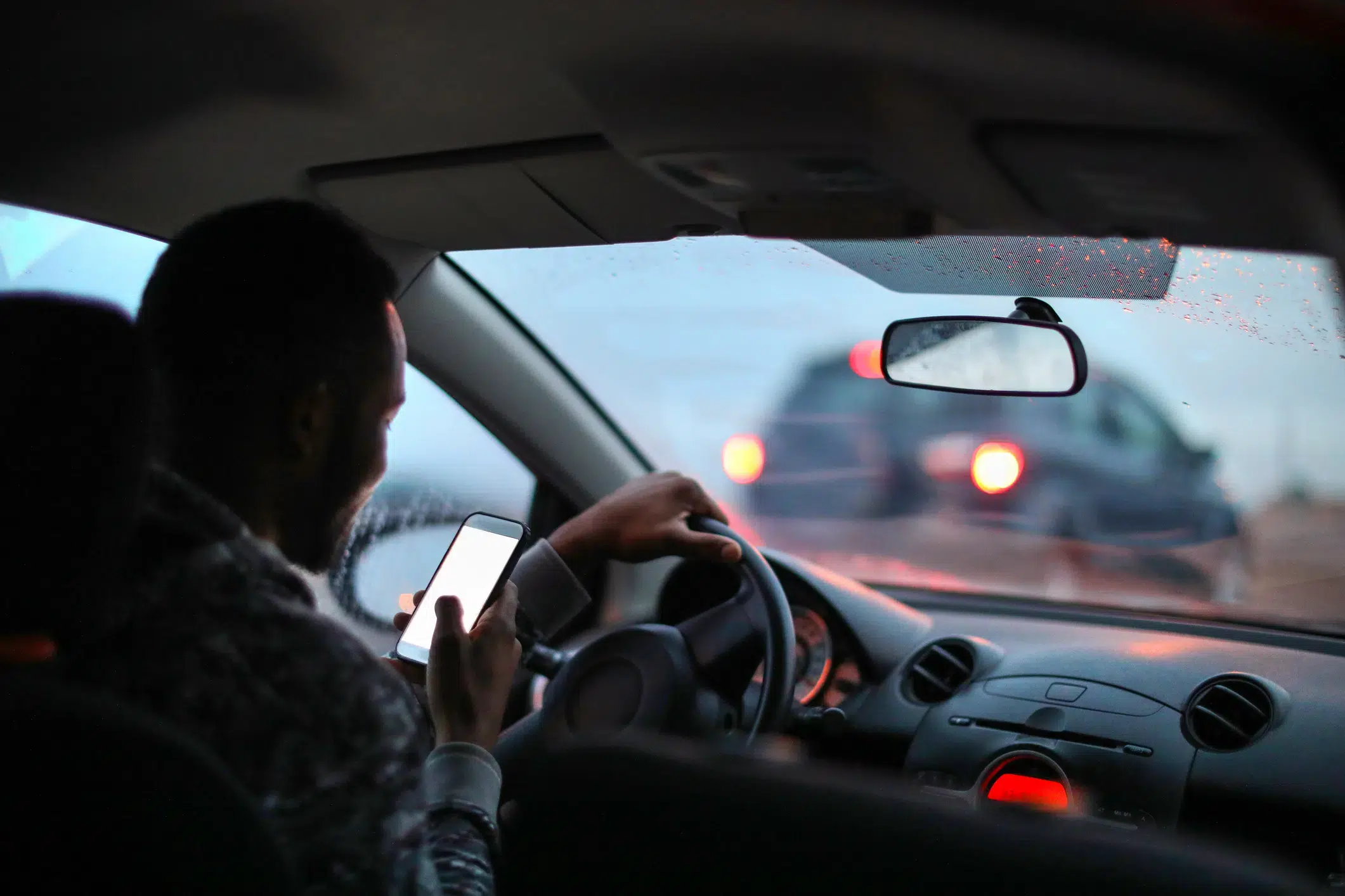 A person texting on smartphone while driving.