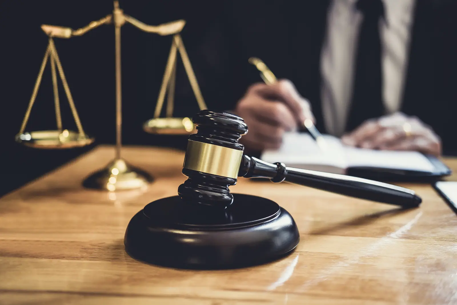 A judge's gavel rests on a wooden table with scales of justice in the background.