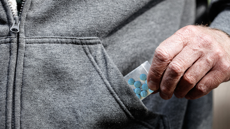 fentanyl oxycodone opioid in plastic bag in hand holding by pocket of jacket