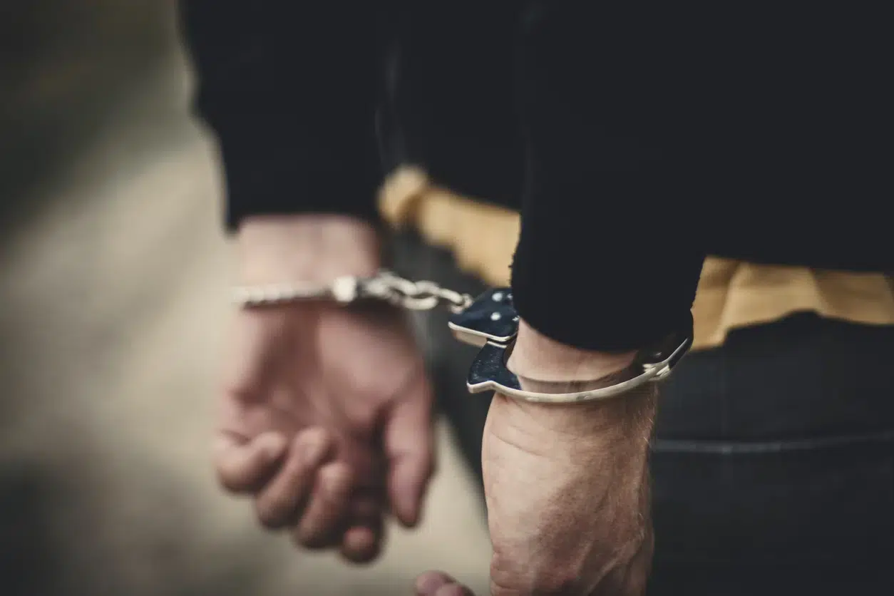 A person with hands behind their back in handcuffs. Arrested for probation violation